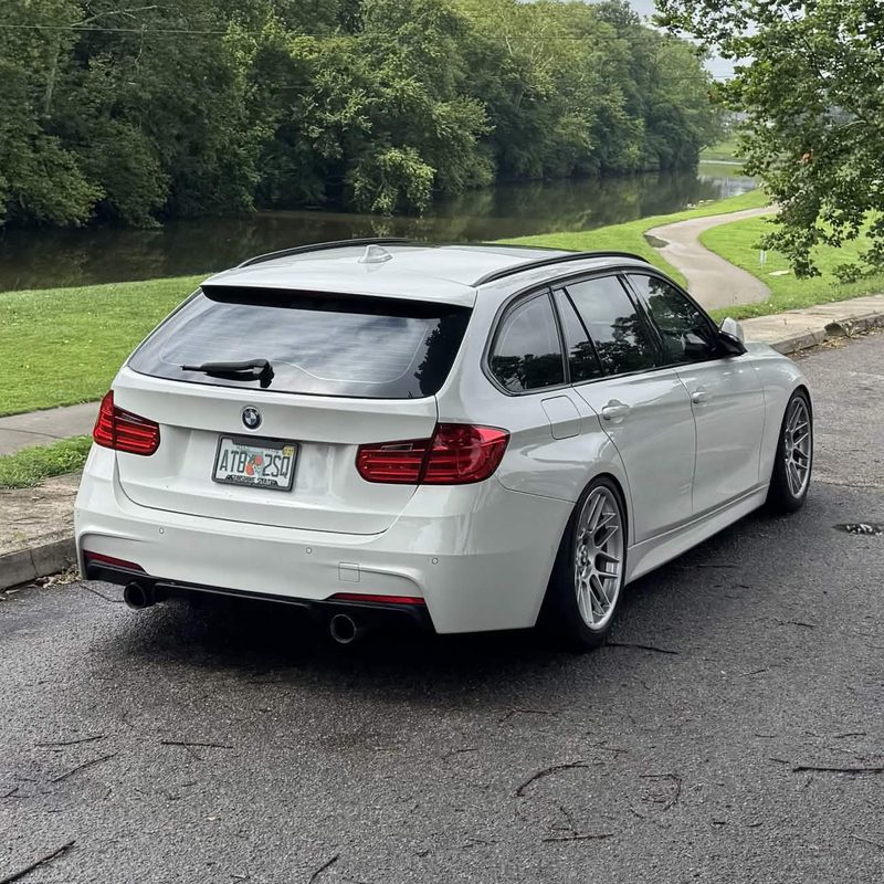 White BMW 3 Series wagon parked on a riverside road